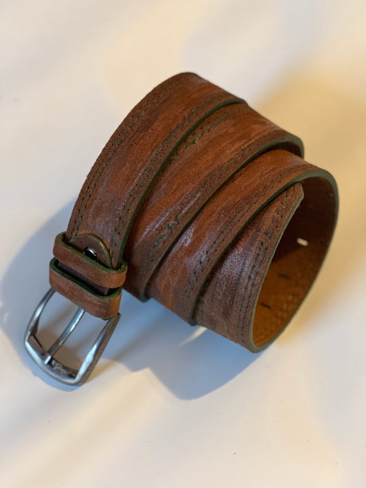 A brown leather belt with a classic buckle, showcasing an interplay of colors and patterns, with dark green stitching.